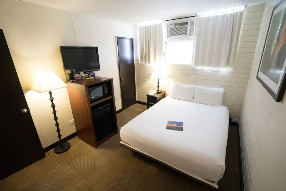 Petite Room with double bed, TV, mini fridge, microwave, and window AC at Stay Hotel Waikiki.