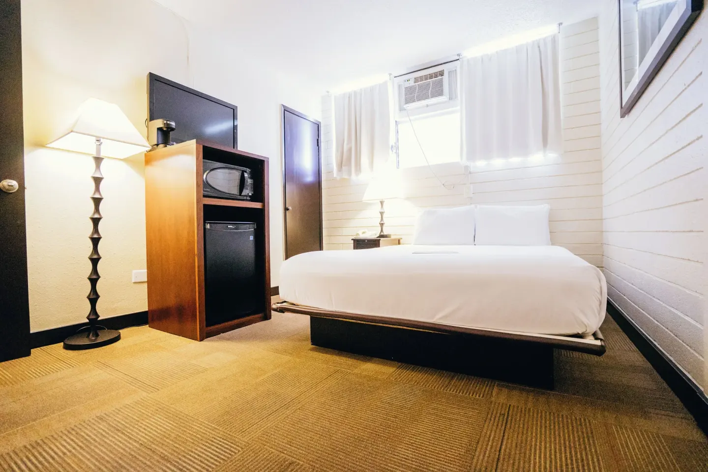 Petite Room with double bed, floor lamp, TV cabinet, microwave, and mini fridge at Stay Hotel Waikiki.
