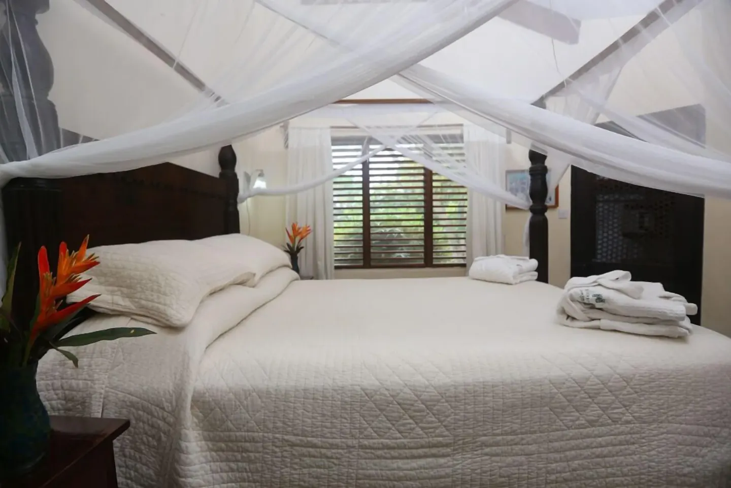 Close view of a white canopy bed with folded towels at Stonefield Villa Resort.
