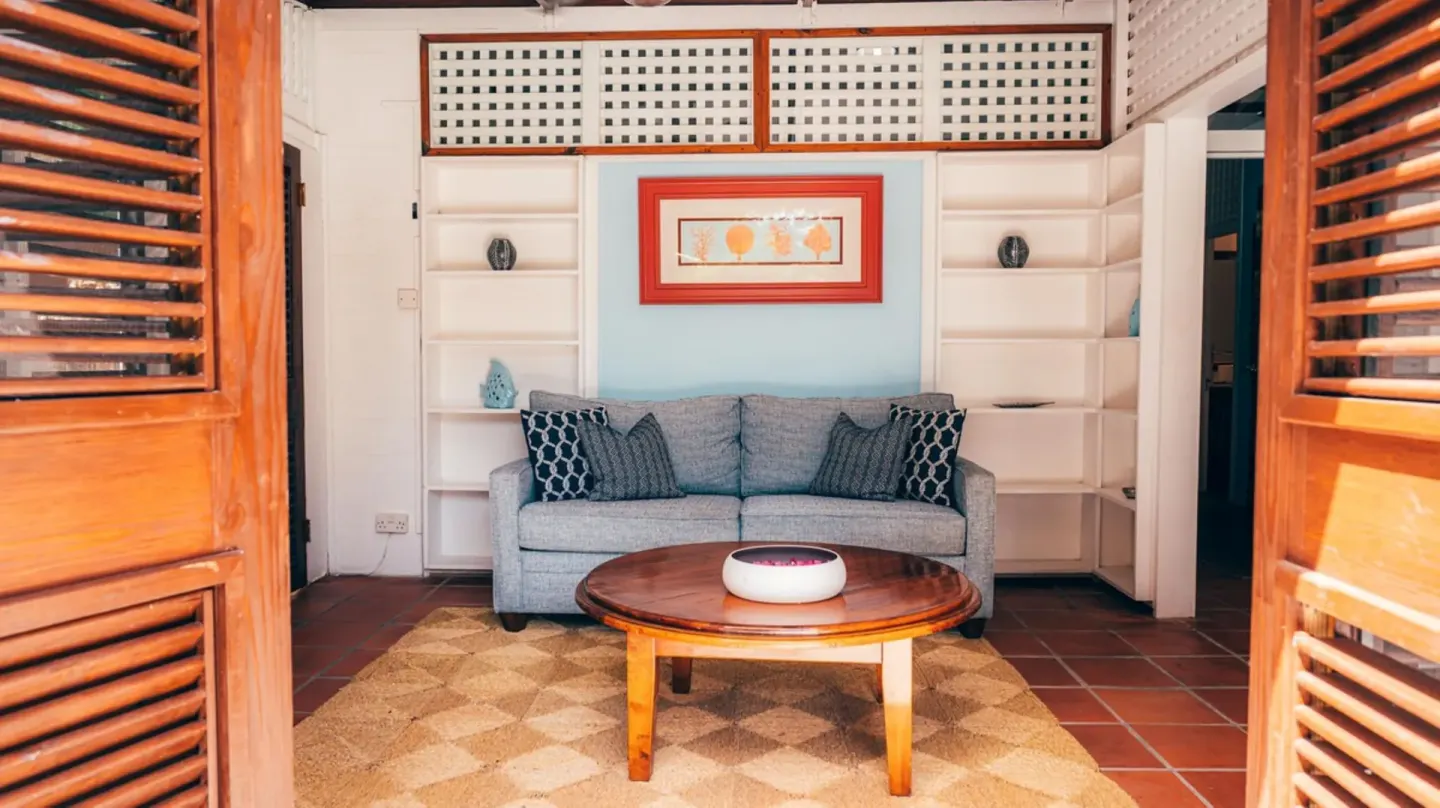 Compact villa sitting area with gray sofa and wood shutters at Stonefield Villa Resort.
