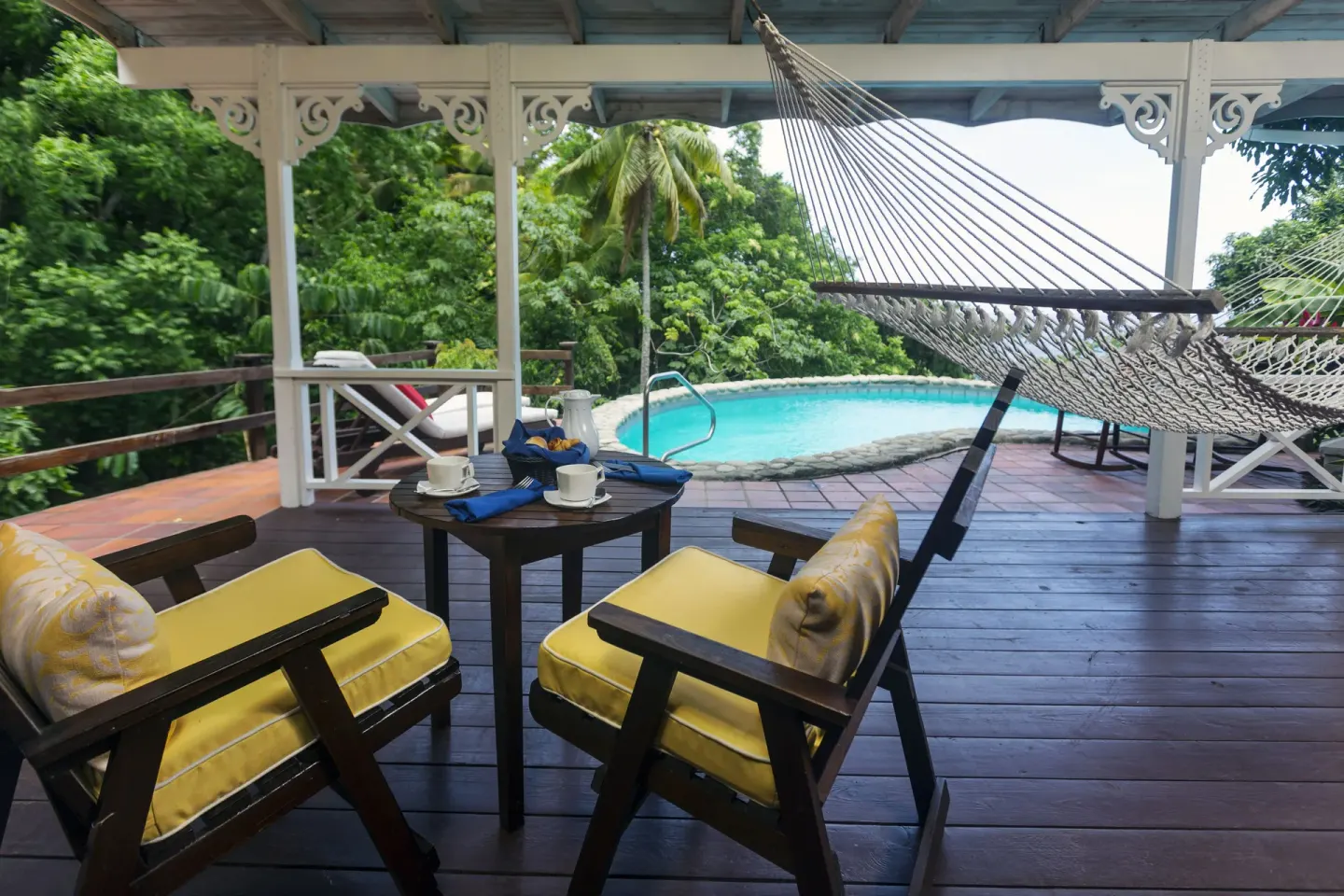 Covered villa veranda with hammock, chairs and pool at Stonefield Villa Resort.