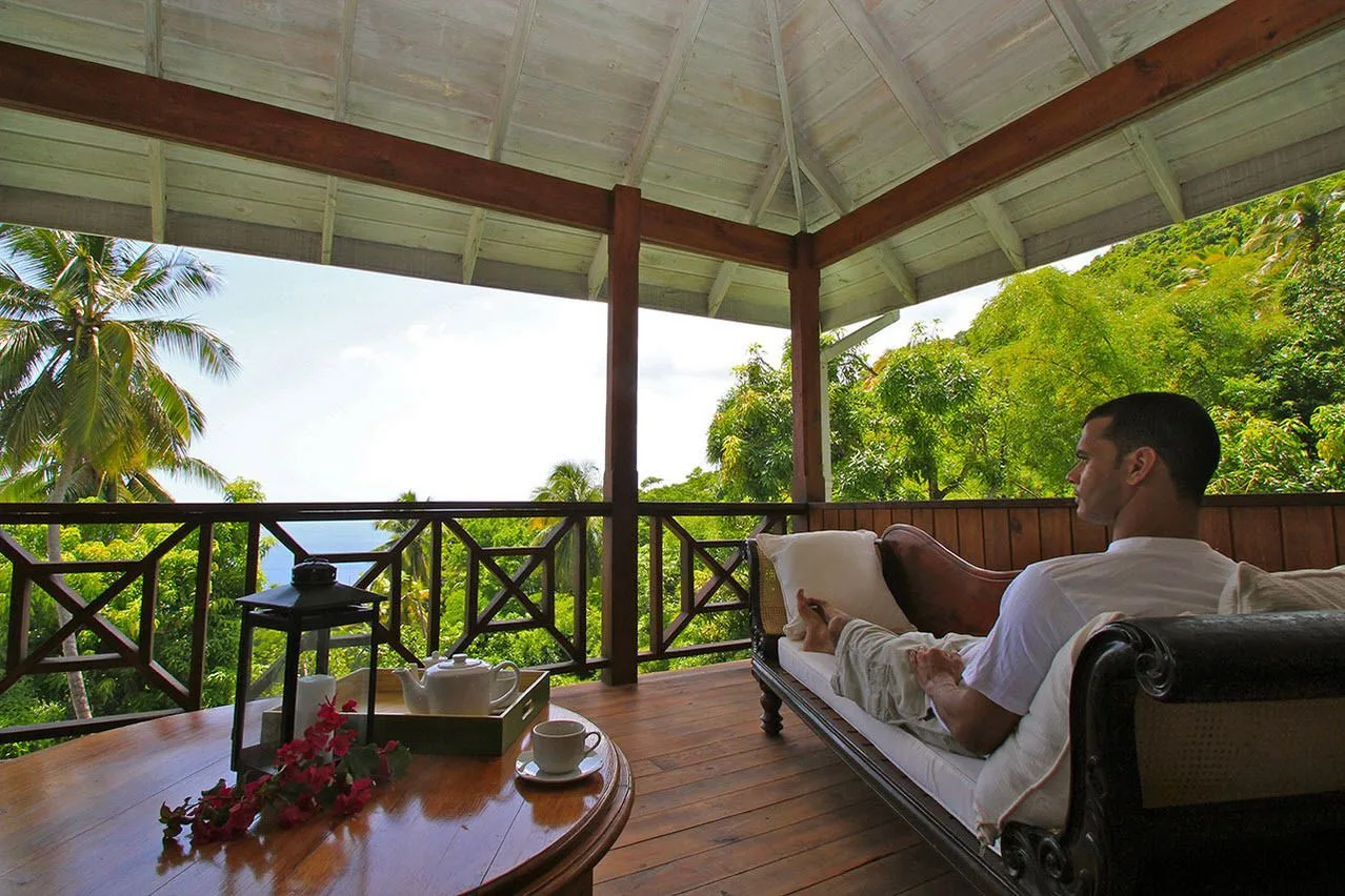 Guest relaxing on a covered villa veranda with tea and tropical views at Stonefield Villa Resort.
