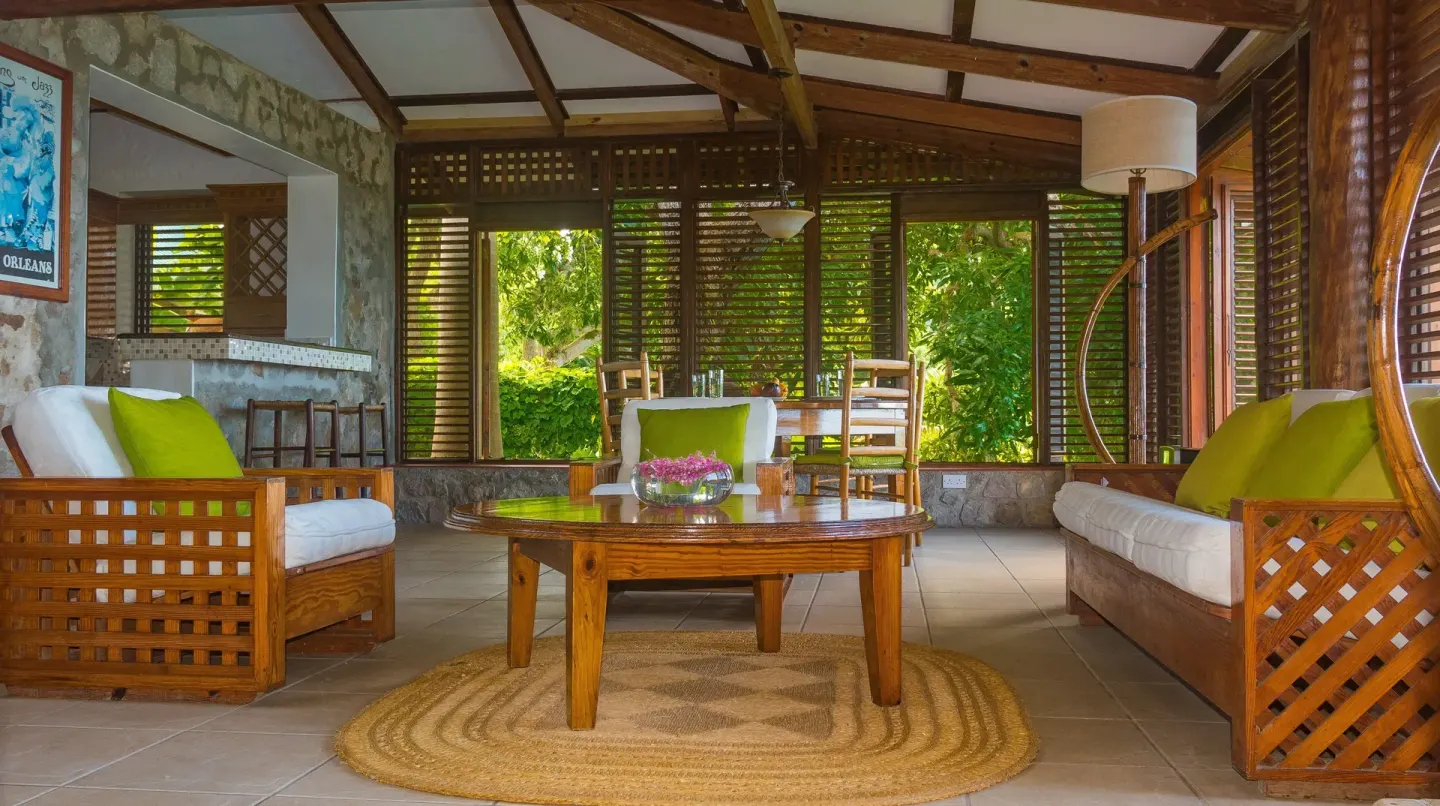 Open-air lounge with wood seating, green pillows and garden views at Stonefield Villa Resort.