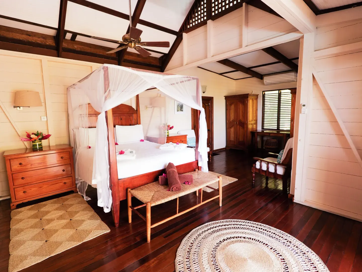 Spacious guest room with canopy bed and wood-beamed ceiling at Stonefield Villa Resort.