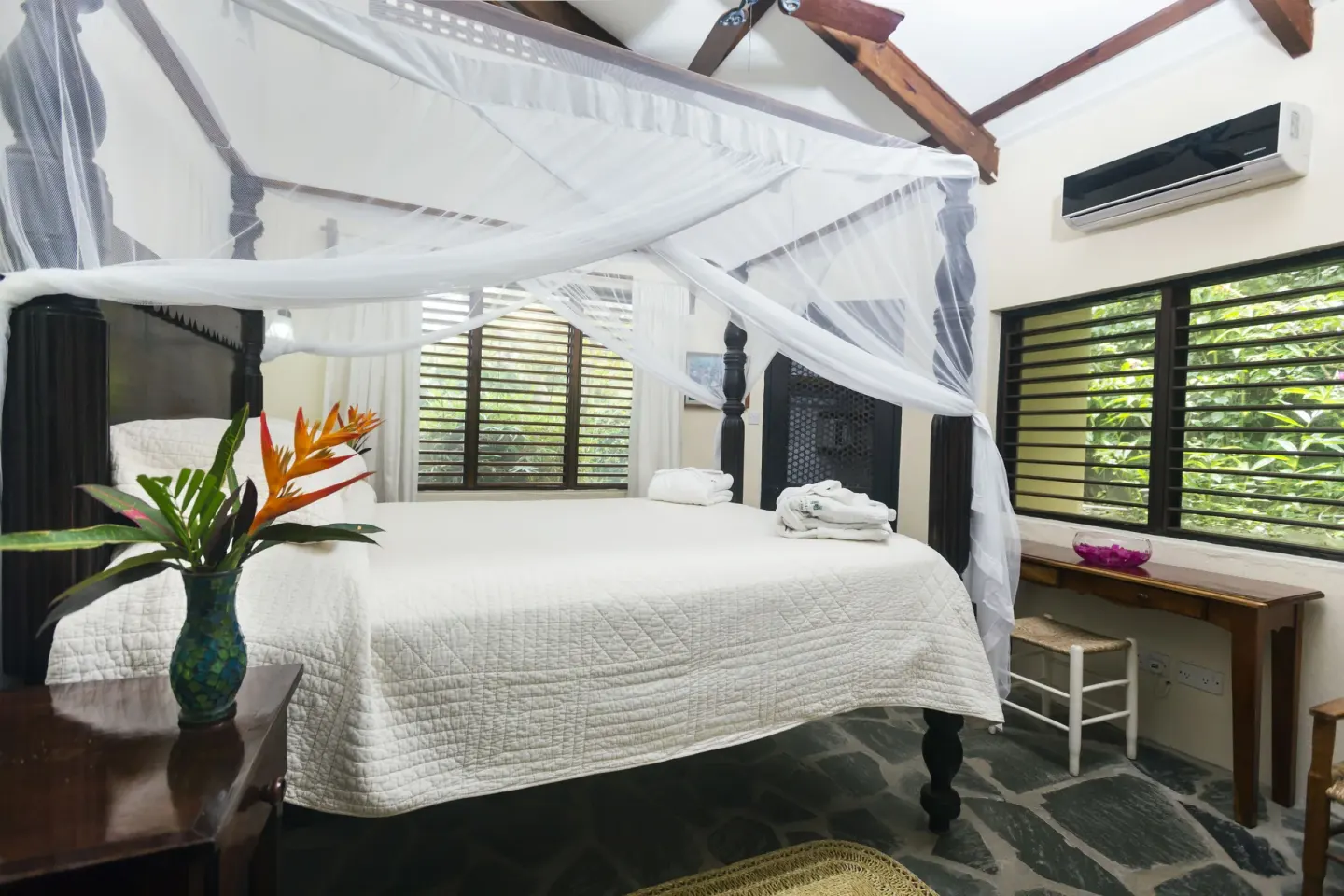 Guest room with a net-draped four-poster bed at Stonefield Villa Resort.