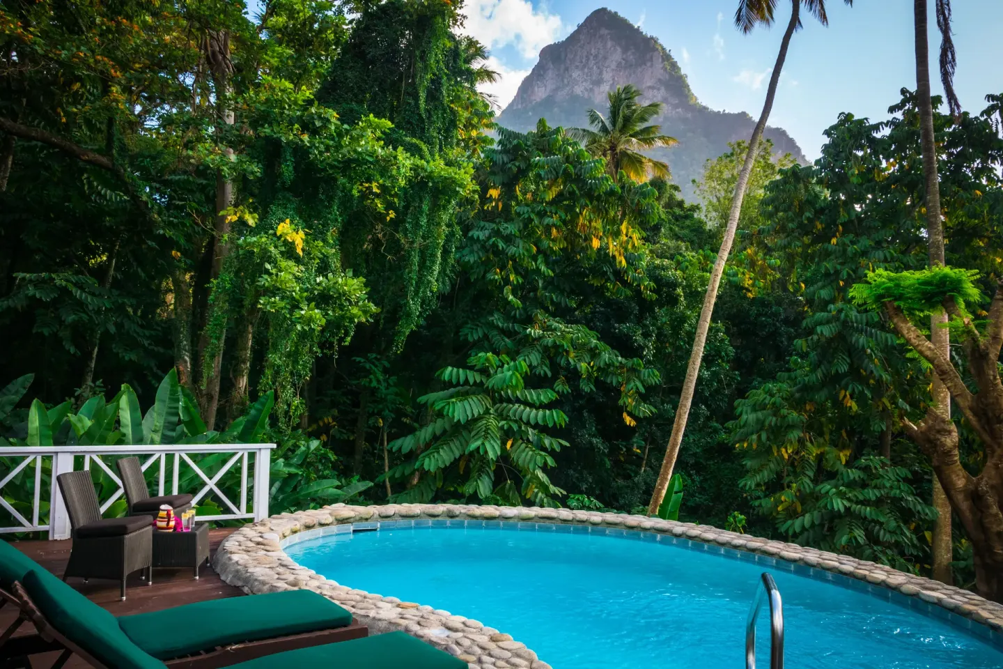 Round pool surrounded by loungers, palms and mountain greenery at Stonefield Villa Resort.