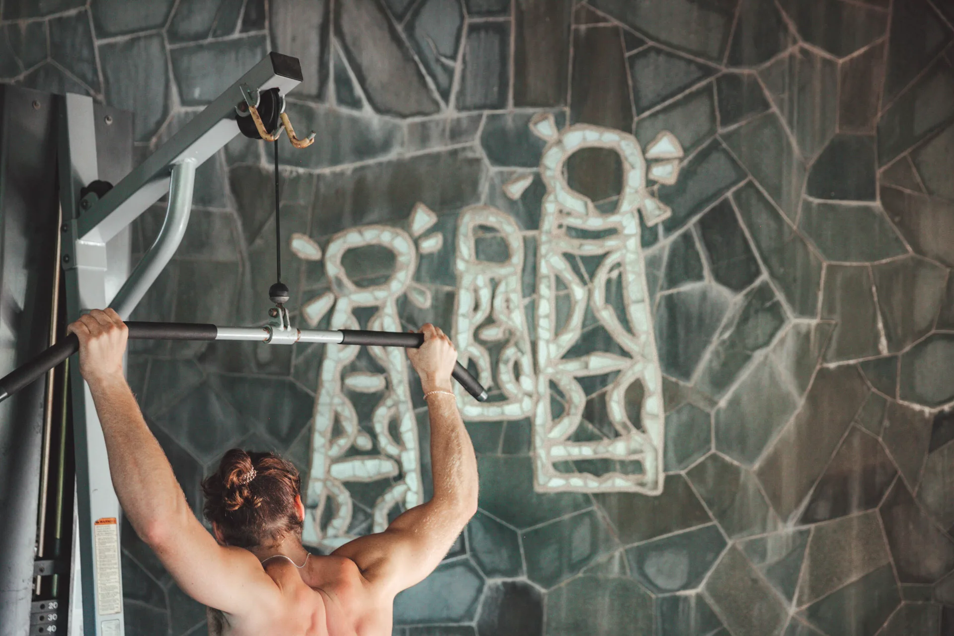 Guest performs a lat pulldown in the fitness room at Stonefield Villa Resort.
