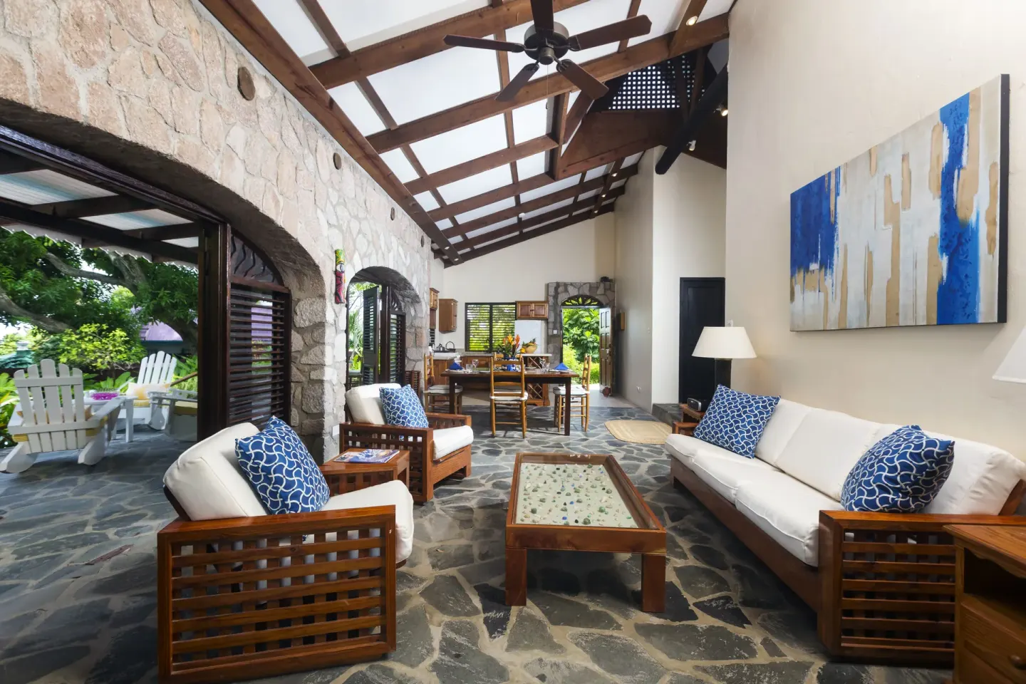 Open villa living room with stone wall and white seating at Stonefield Villa Resort.