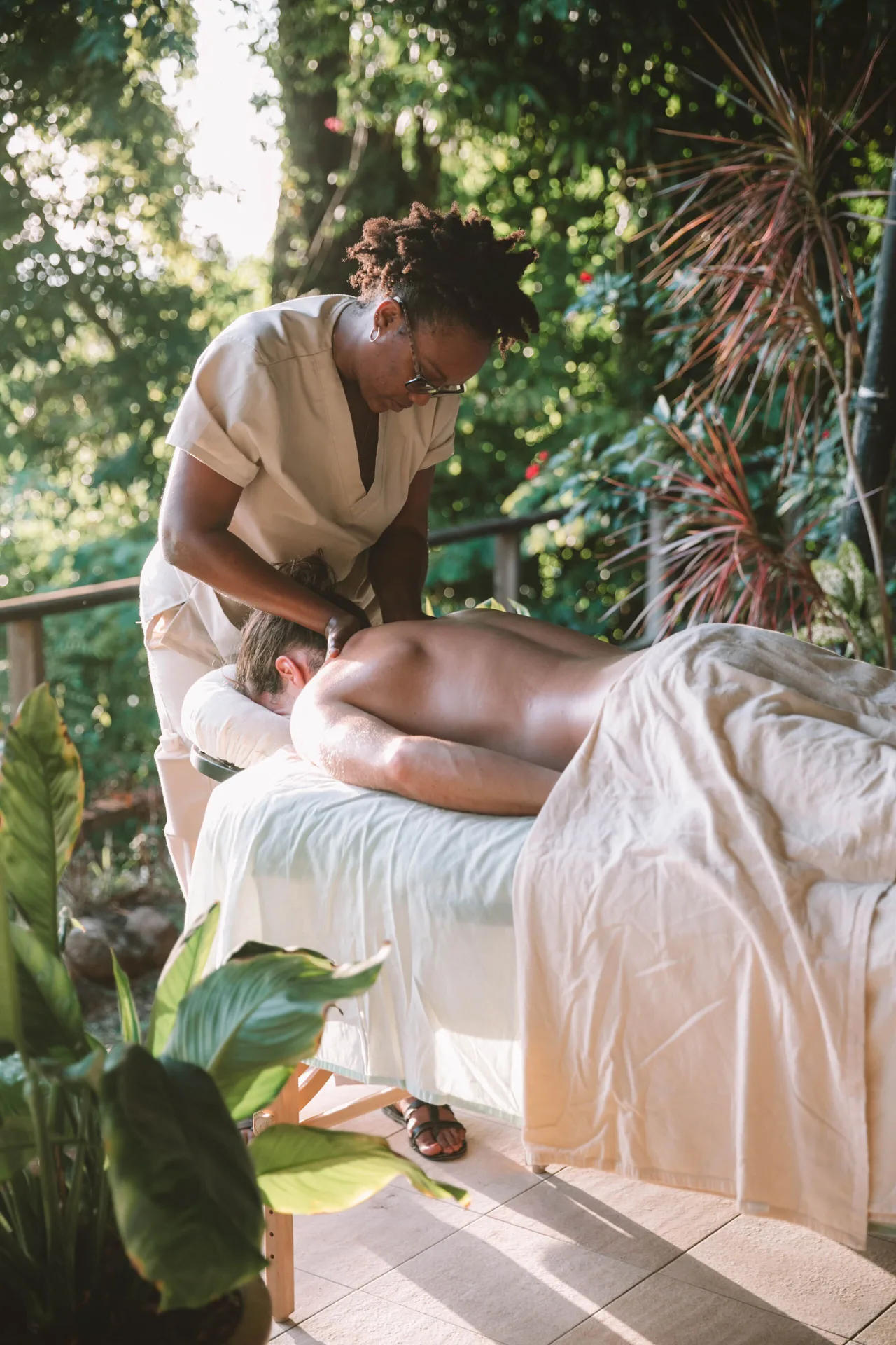 Therapist giving an outdoor massage amid tropical plants at Stonefield Villa Resort.