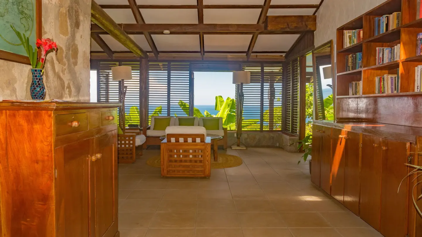 Resort lounge with wood cabinets, bookshelves and sea-facing shutters at Stonefield Villa Resort.