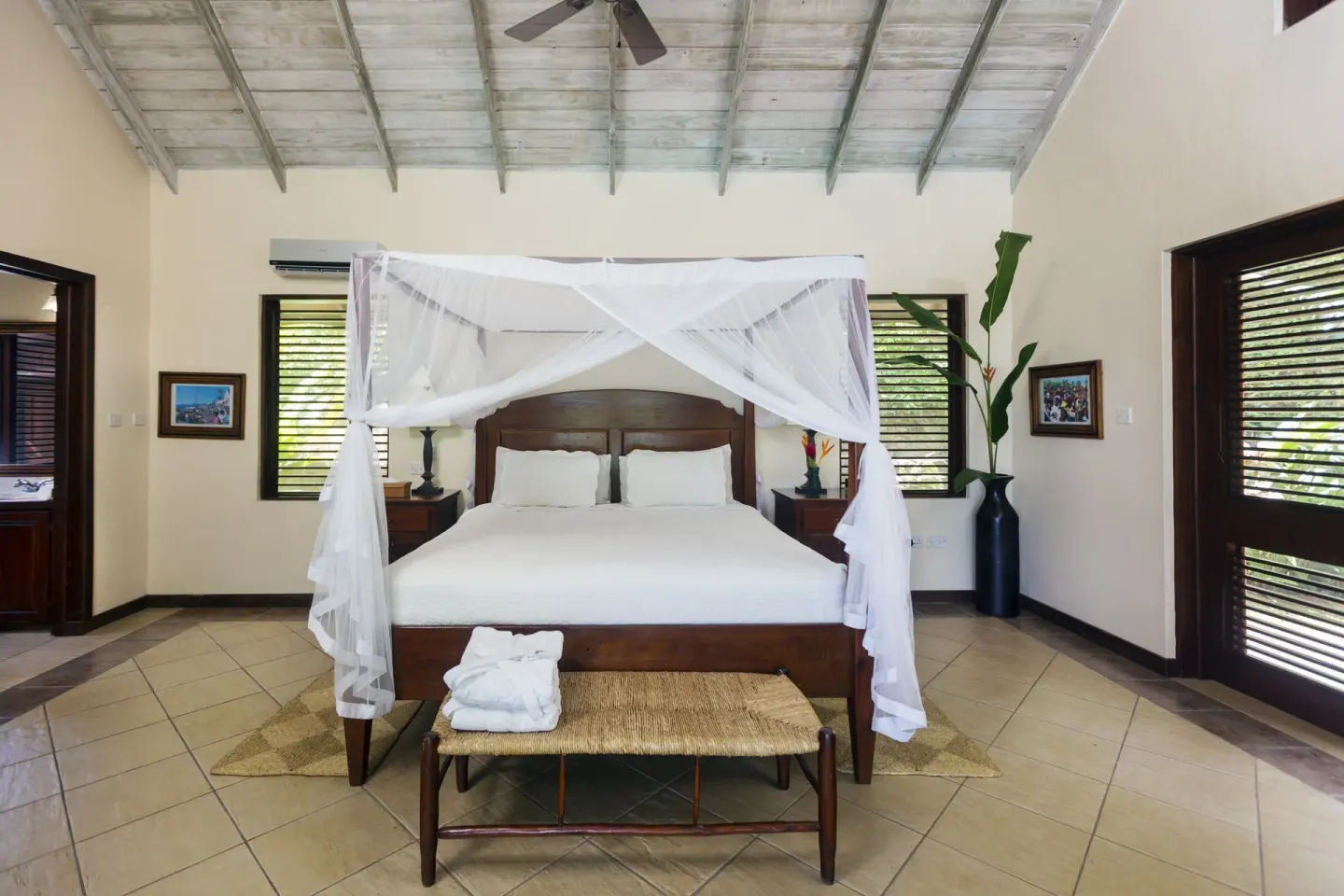 Spacious villa bedroom with a white-draped canopy bed at Stonefield Villa Resort.