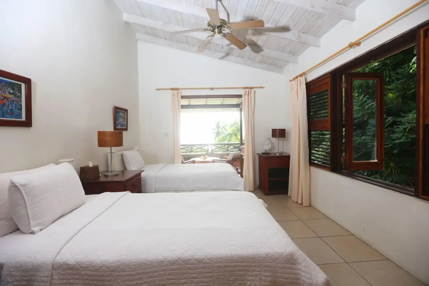 Two-bed guest room with open windows and a balcony beyond at Stonefield Villa Resort.