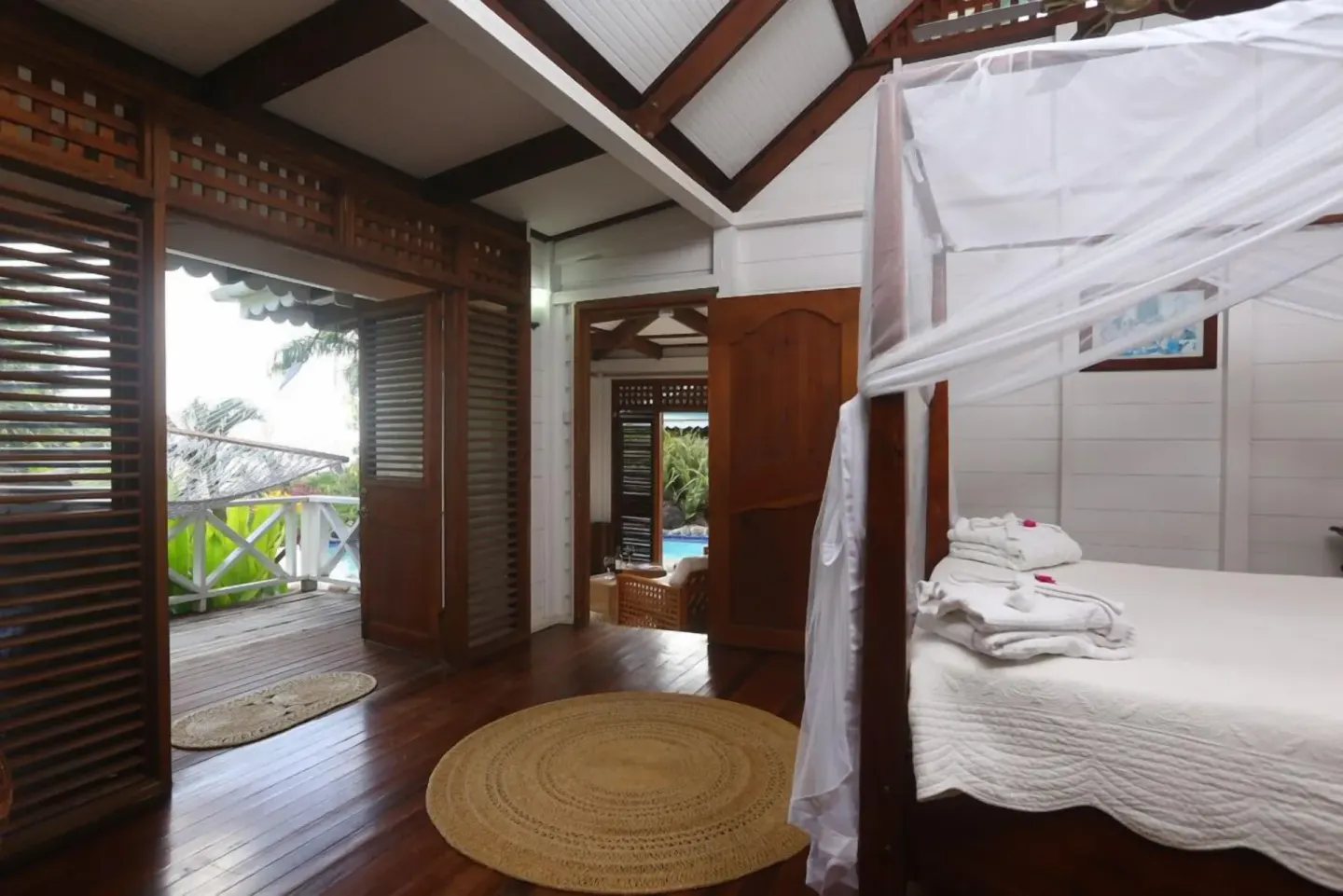 Canopy bed in a wood-floored villa bedroom with balcony access at Stonefield Villa Resort.