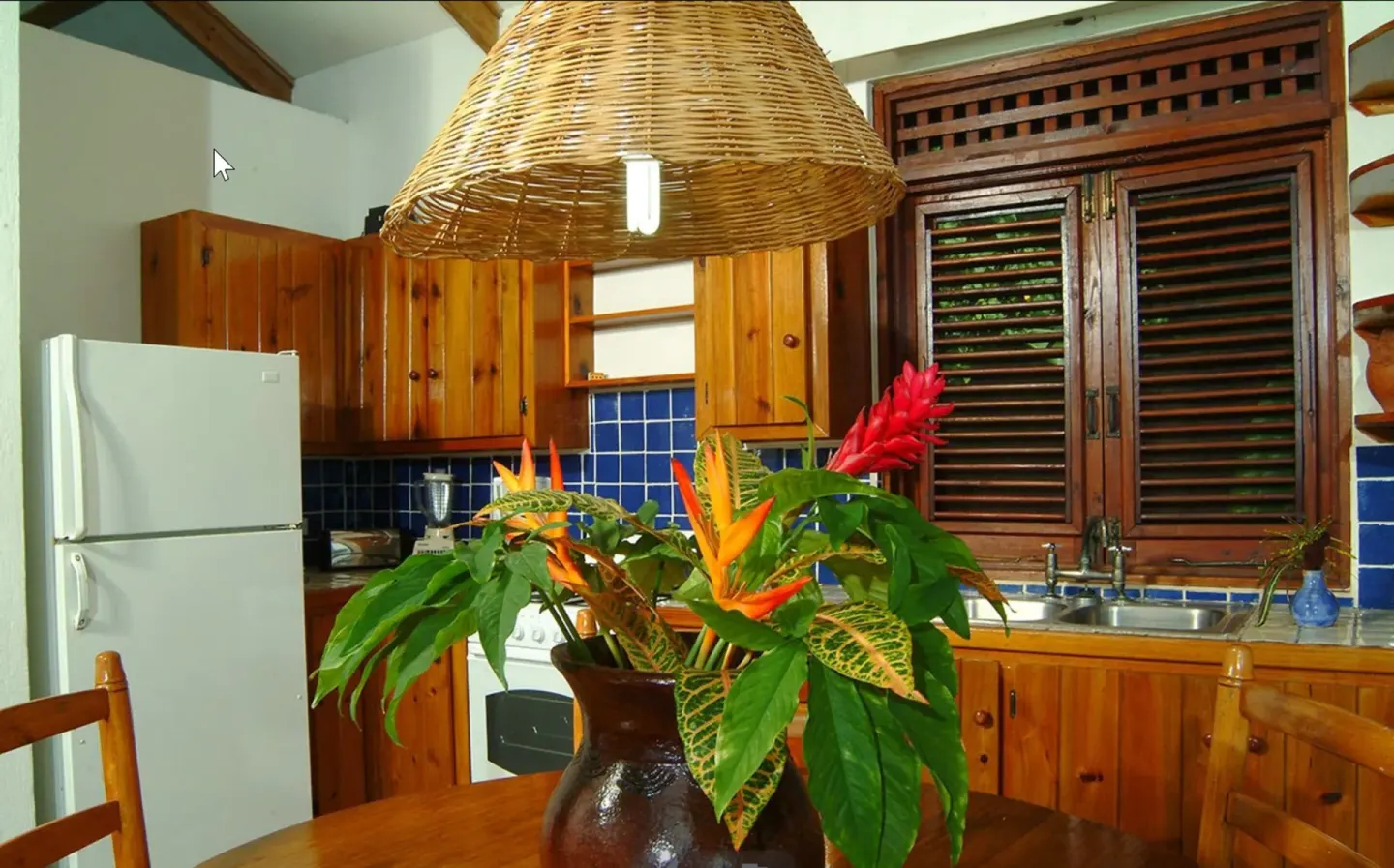 Villa kitchen with wood cabinets, blue tile, and floral arrangement at Stonefield Villa Resort.