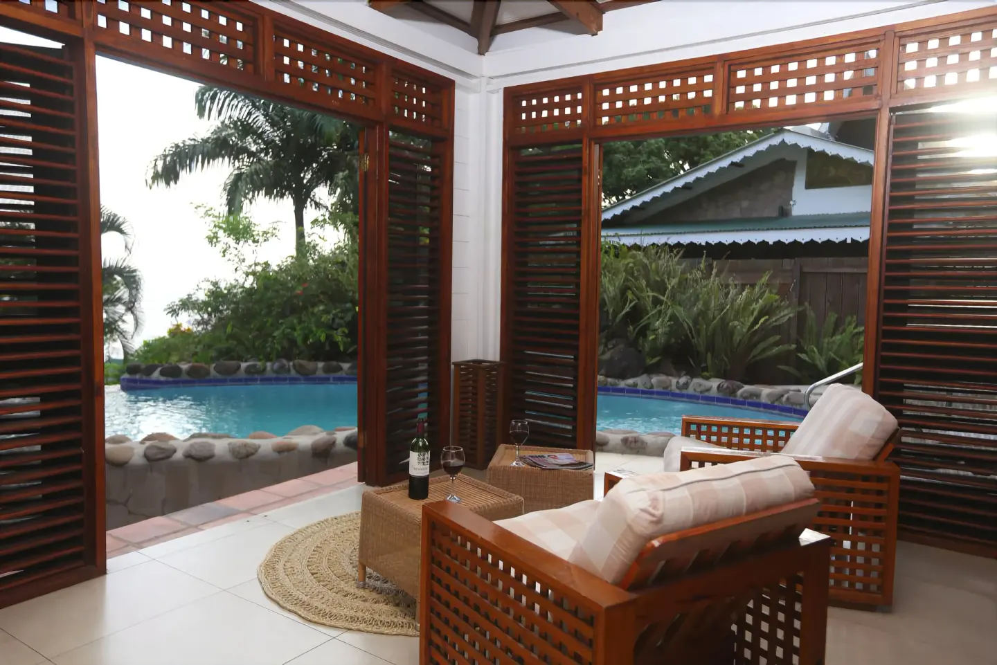 Villa lounge with open shutters beside a private pool at Stonefield Villa Resort.