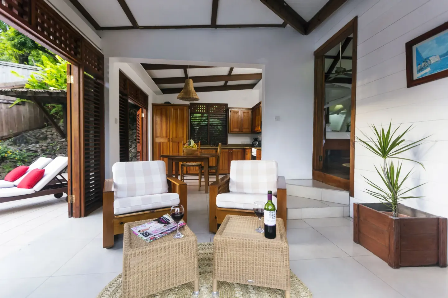 Villa sitting area with wicker tables, armchairs, and kitchen beyond at Stonefield Villa Resort.