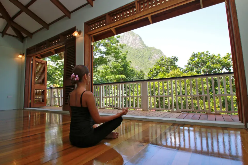 Guest meditates in an open yoga room with mountain views at Stonefield Villa Resort.
