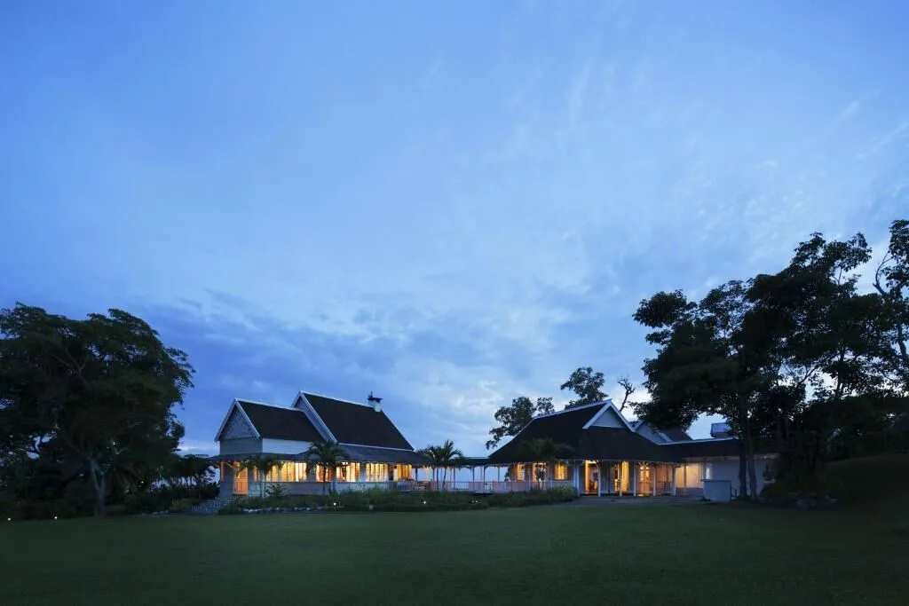Lit resort buildings at Strawberry Hill sit beside a broad lawn at dusk.