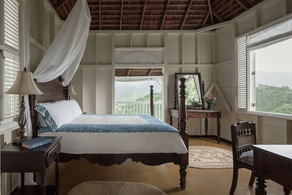 A four-poster bed and open mountain-view windows in a guest room at Strawberry Hill.