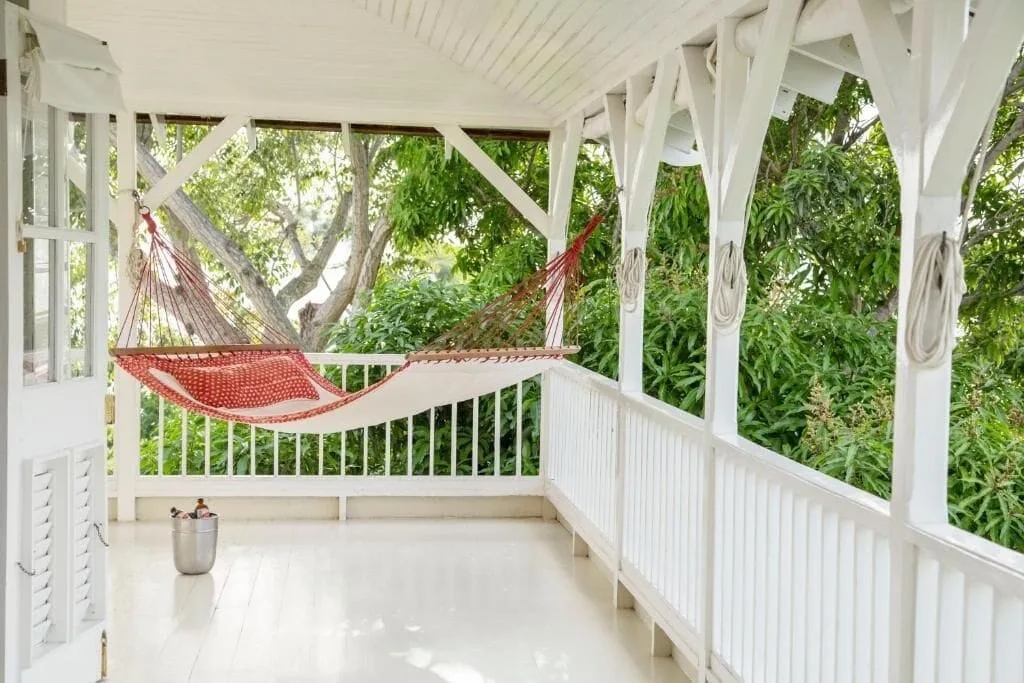 A white veranda with two red hammocks overlooking greenery at Strawberry Hill.