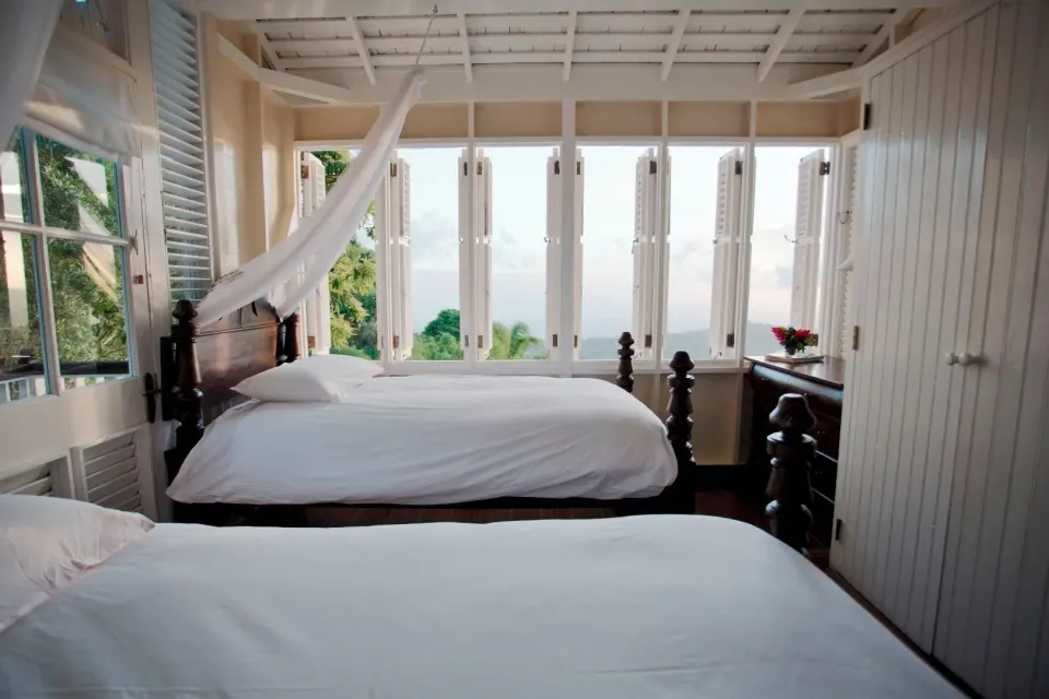 Two white beds in a Cottage 2 Bedrooms room at Strawberry Hill with wide windows and hillside views.