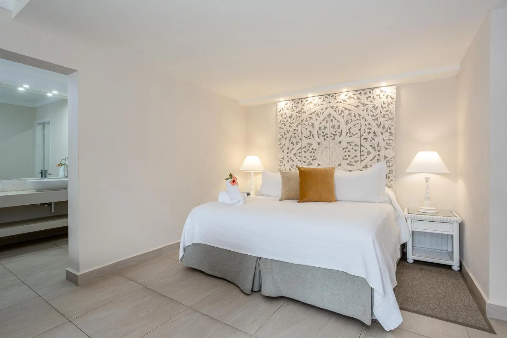 White king bed and open bathroom area in a guest room at Sugar Bay Barbados.