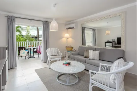 Guest room sitting area with sofa, wicker chairs and balcony at Sugar Bay Barbados.