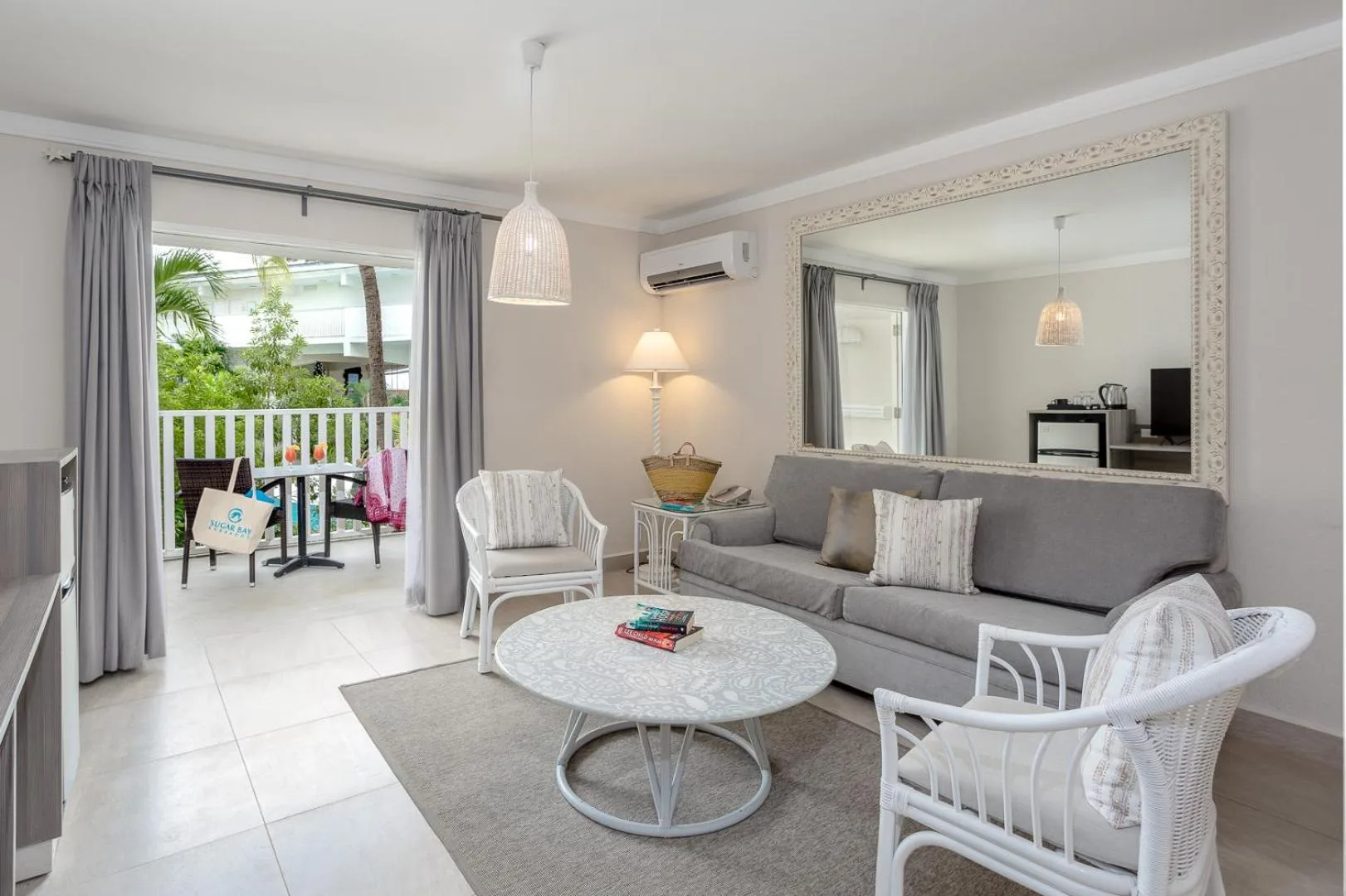 Guest room sitting area with sofa, wicker chairs and balcony at Sugar Bay Barbados.