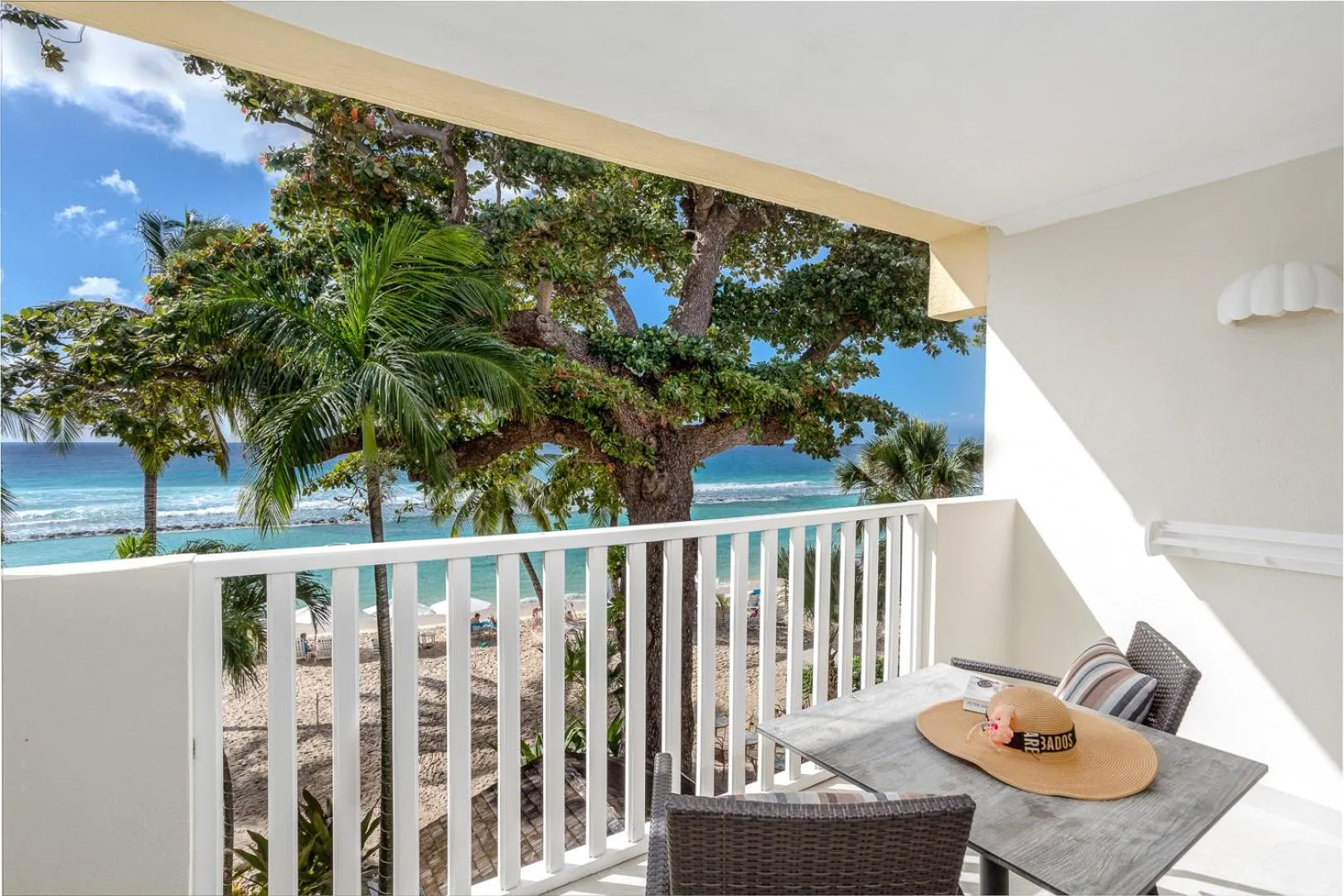 Furnished balcony overlooking beach, palms, and ocean at Sugar Bay Barbados.