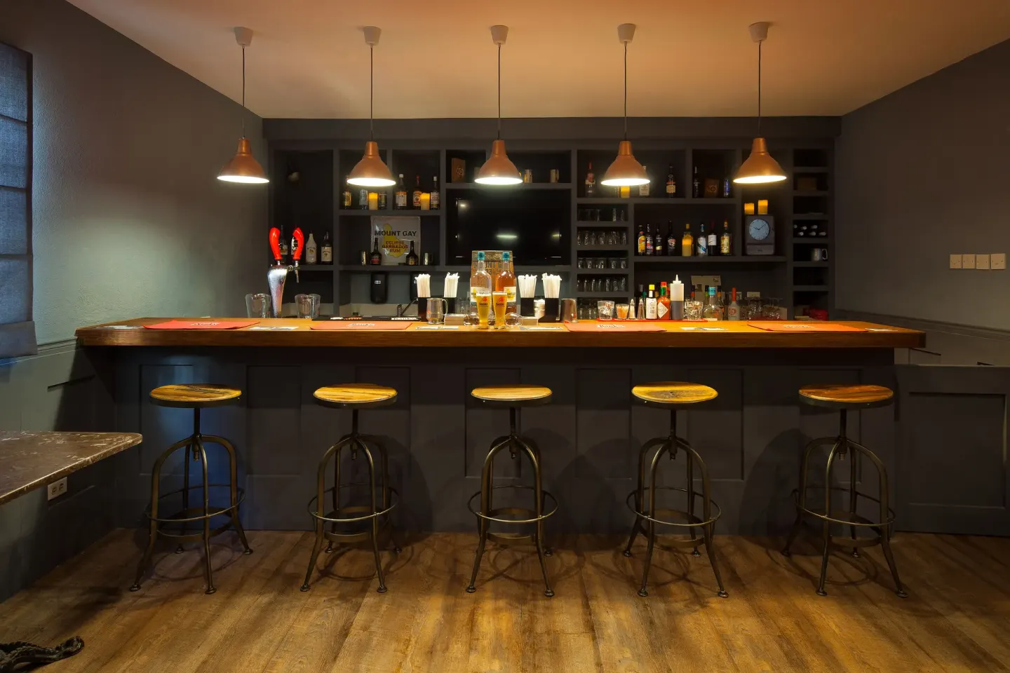 Dark indoor pub bar with stools and pendant lights at Sugar Bay Barbados.