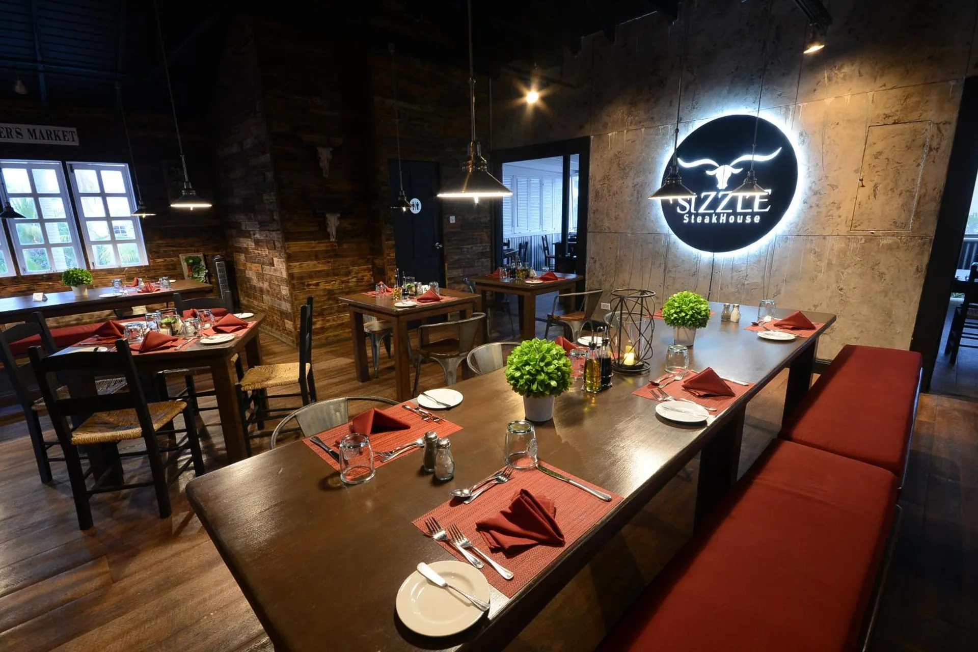 Sizzle Steakhouse dining room with set tables and wall sign at Sugar Bay Barbados.