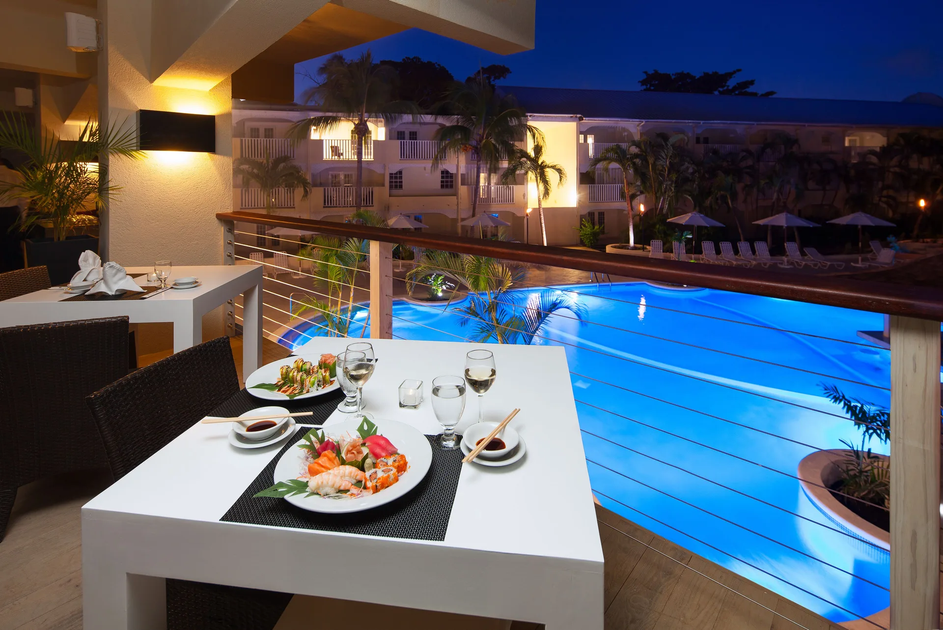 Balcony dining table with sushi overlooking the lit pool at Sugar Bay Barbados.