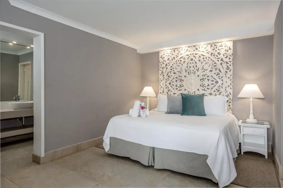 Deluxe Oceanfront Room bed with carved headboard at Sugar Bay Barbados.