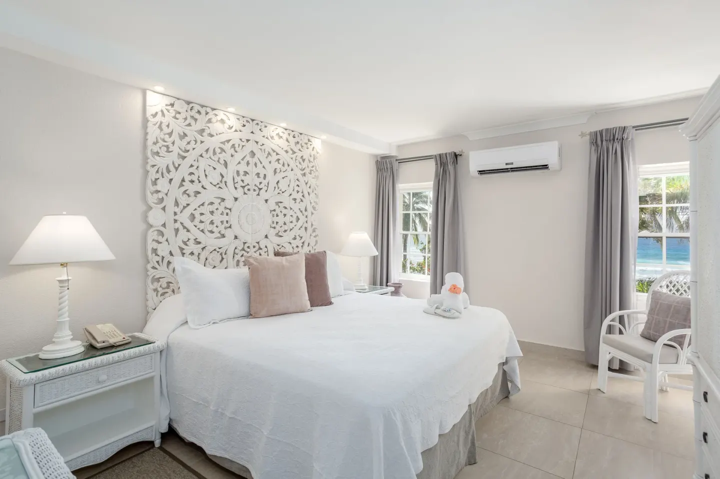 Family Suite Oceanfront bedroom with a king bed and white carved headboard at Sugar Bay Barbados.