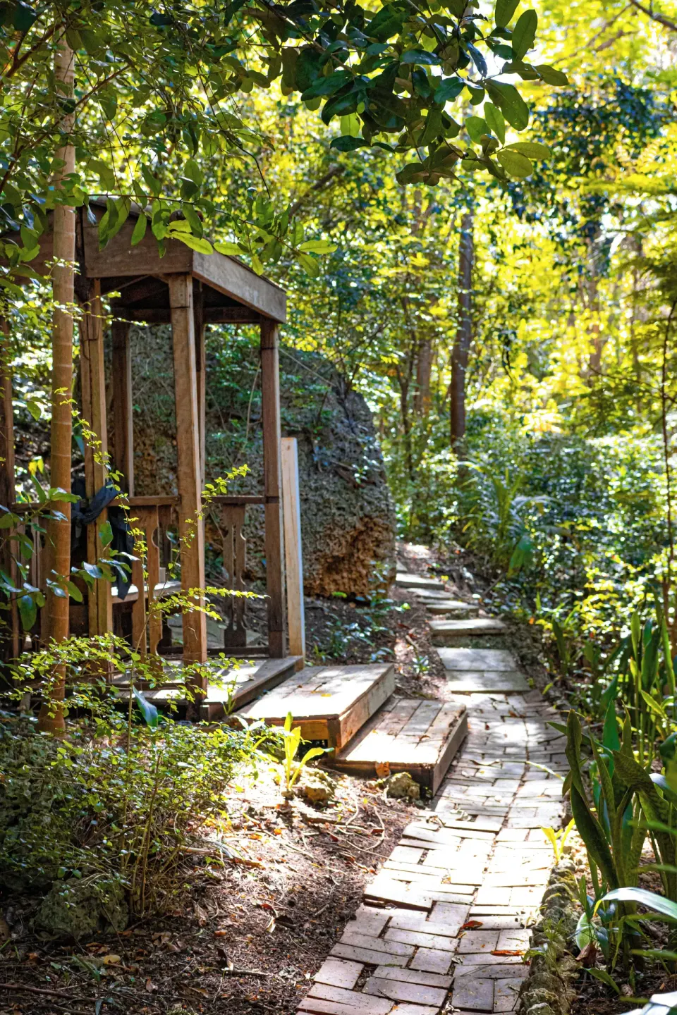 A brick path passes a small wooden pavilion in the gardens at Sugar Cane Club Hotel And Spa.