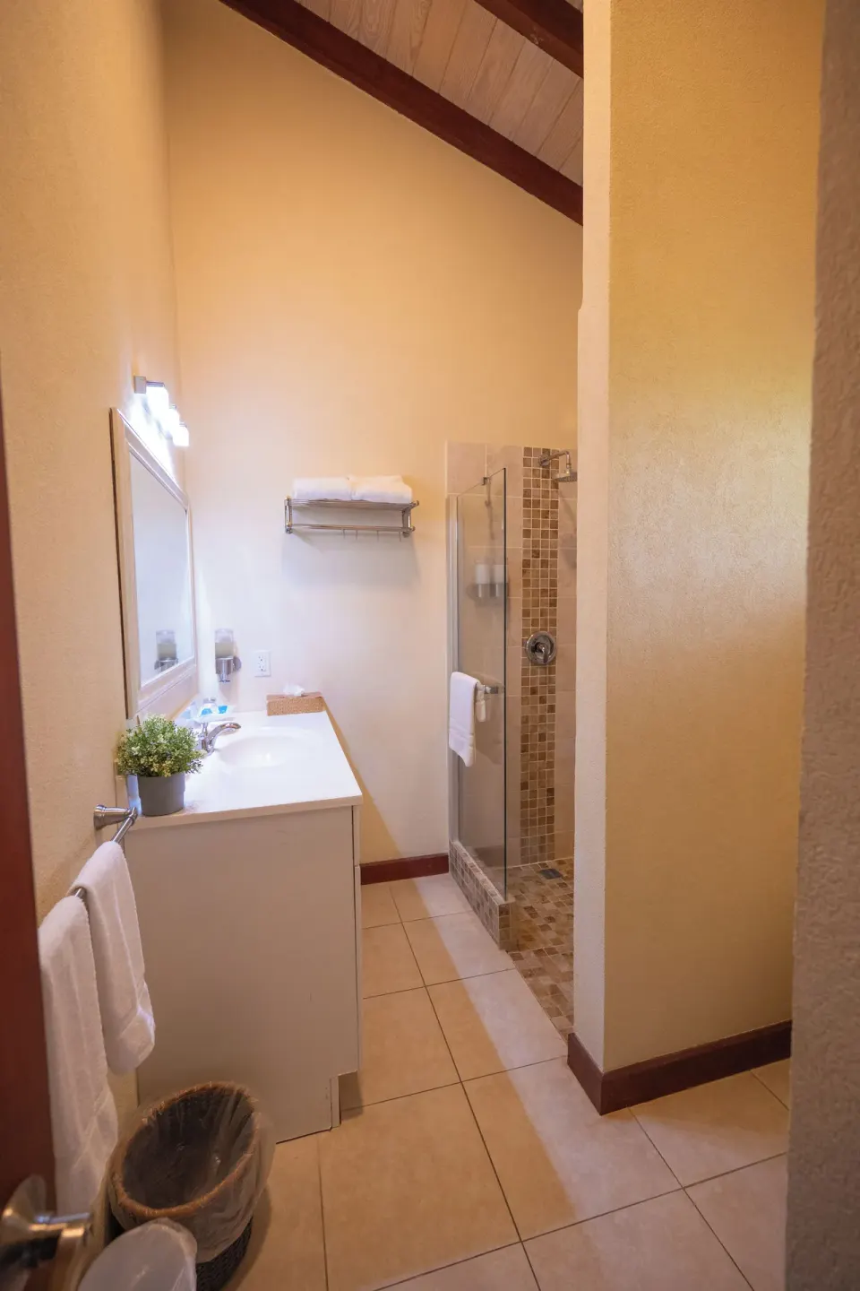 Guest bathroom with vanity, mirror, towels, and glass shower at Sugar Cane Club Hotel And Spa.