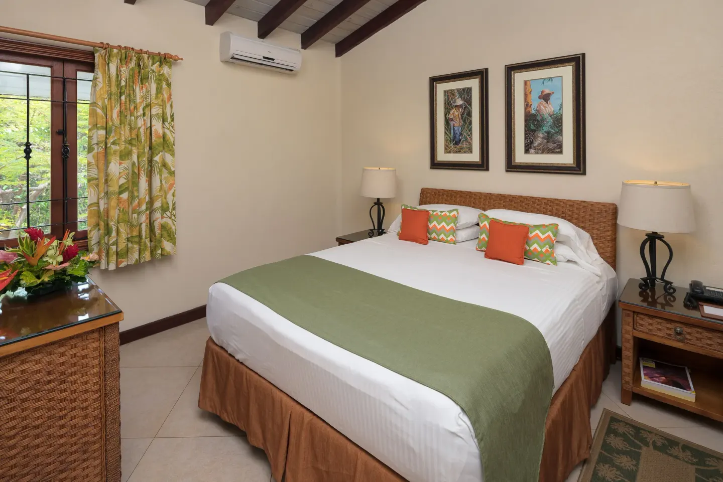 Guest room with a king bed, wicker headboard, and tropical curtains at Sugar Cane Club Hotel And Spa.