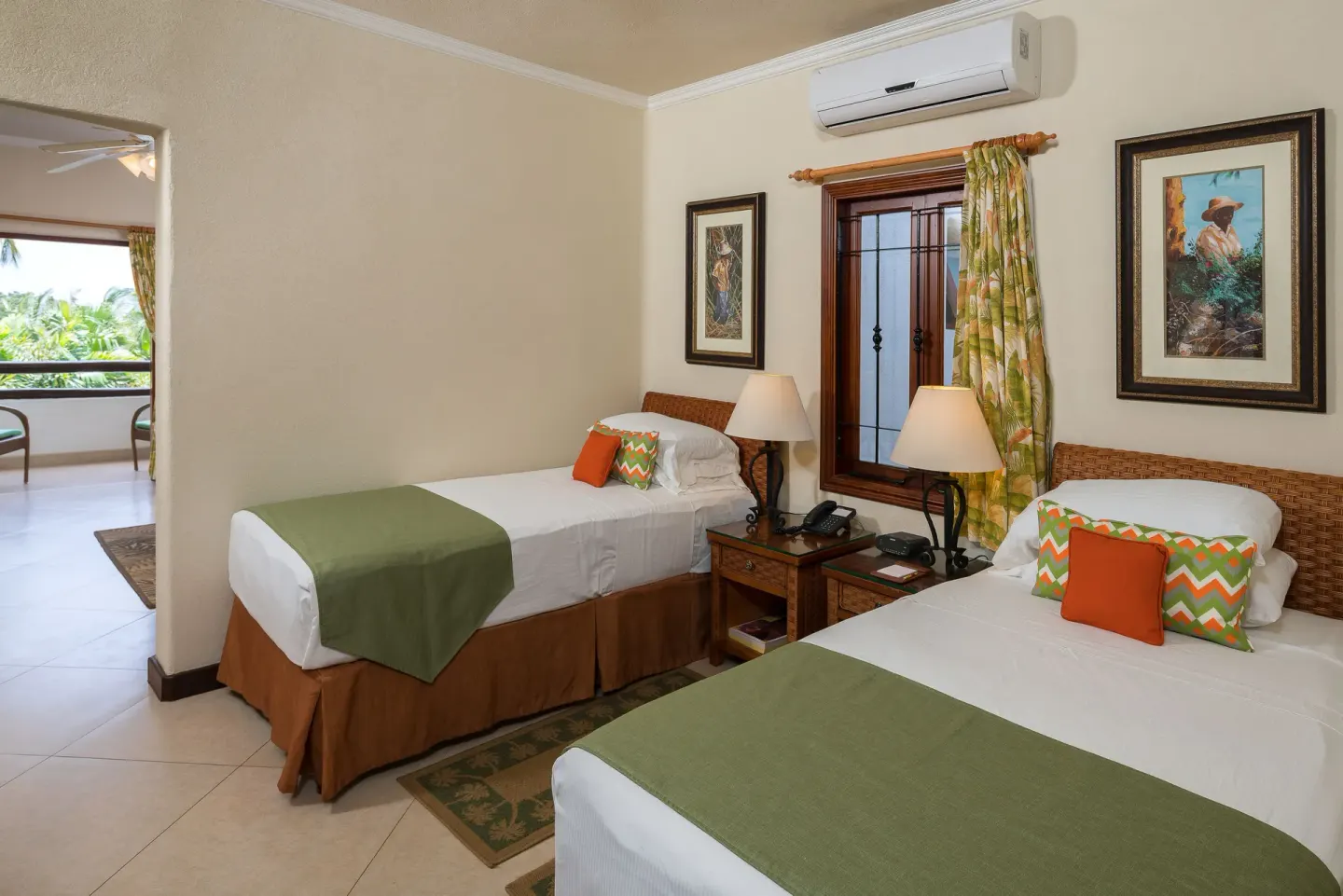 Guest room with two twin beds, bedside lamps, and balcony opening at Sugar Cane Club Hotel And Spa.