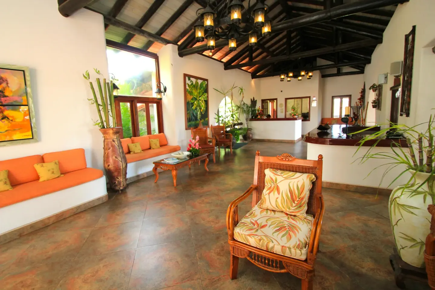 Lobby seating with orange cushions and dark timber ceiling at Sugar Cane Club Hotel And Spa.