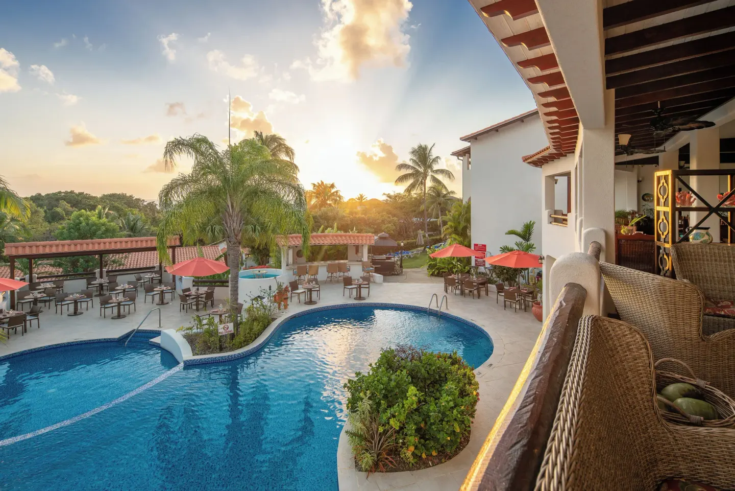 Pool terrace with outdoor tables at sunset at Sugar Cane Club Hotel And Spa.