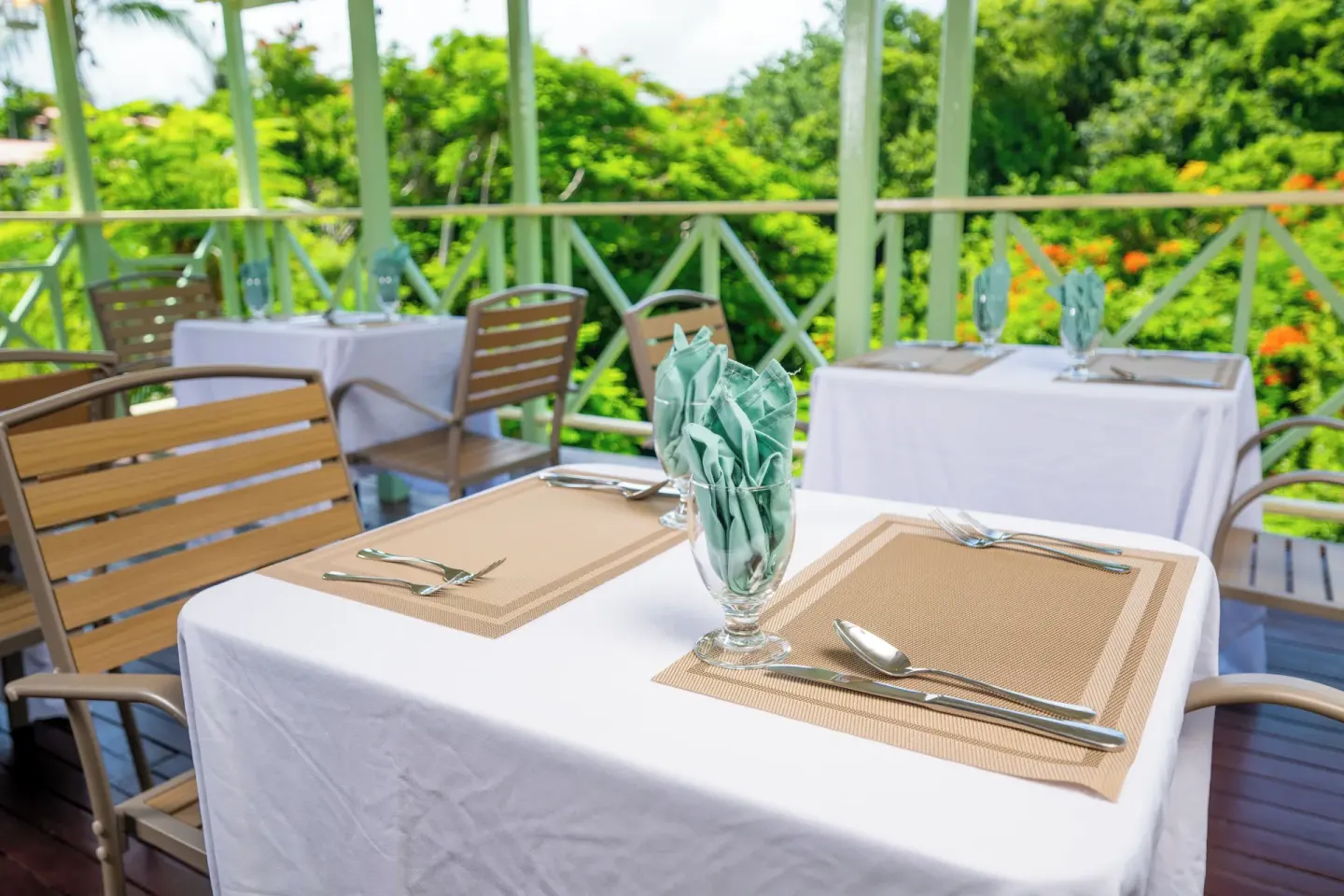 An open-air dining terrace is set with white tablecloths at Sugar Cane Club Hotel And Spa.