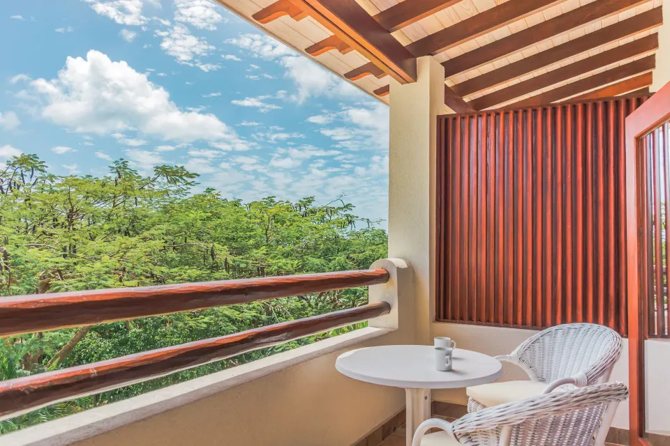 Garden View room balcony with white chairs at Sugar Cane Club Hotel And Spa.