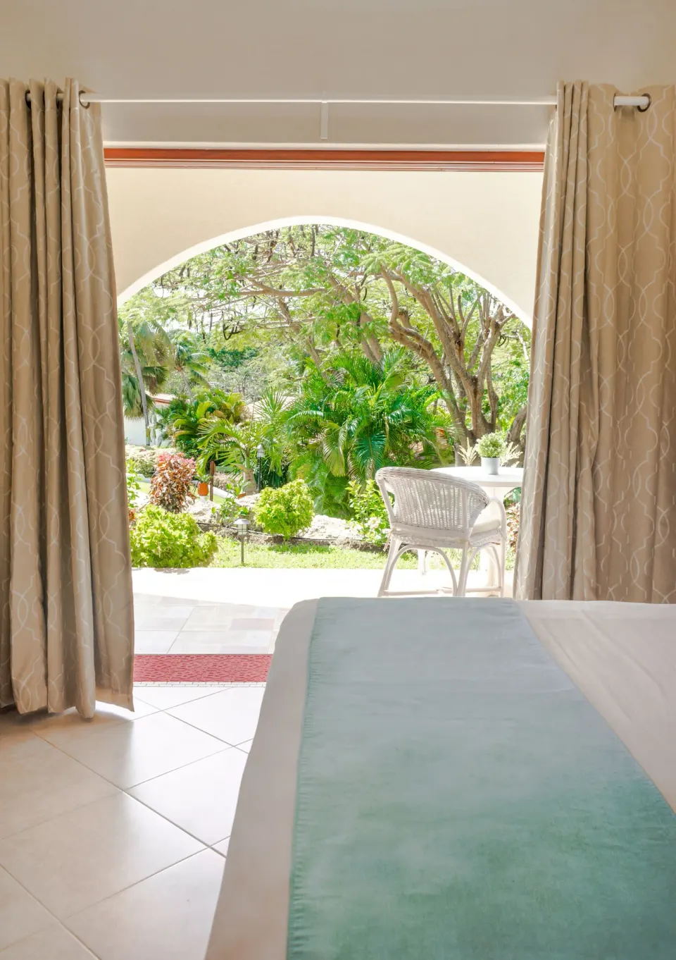 Garden View room bed facing an arched patio at Sugar Cane Club Hotel And Spa.