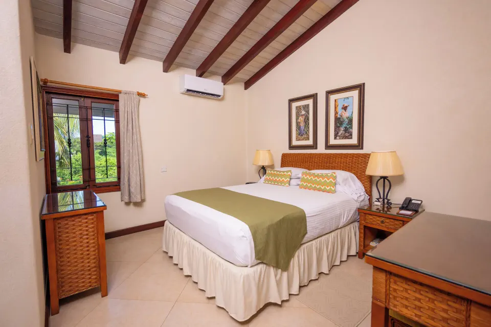 Garden View Suite bedroom with a large bed and beamed ceiling at Sugar Cane Club Hotel And Spa.