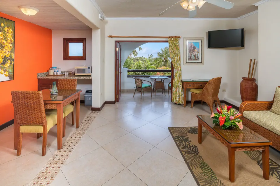 Garden View Suite living area with kitchenette and balcony at Sugar Cane Club Hotel And Spa.