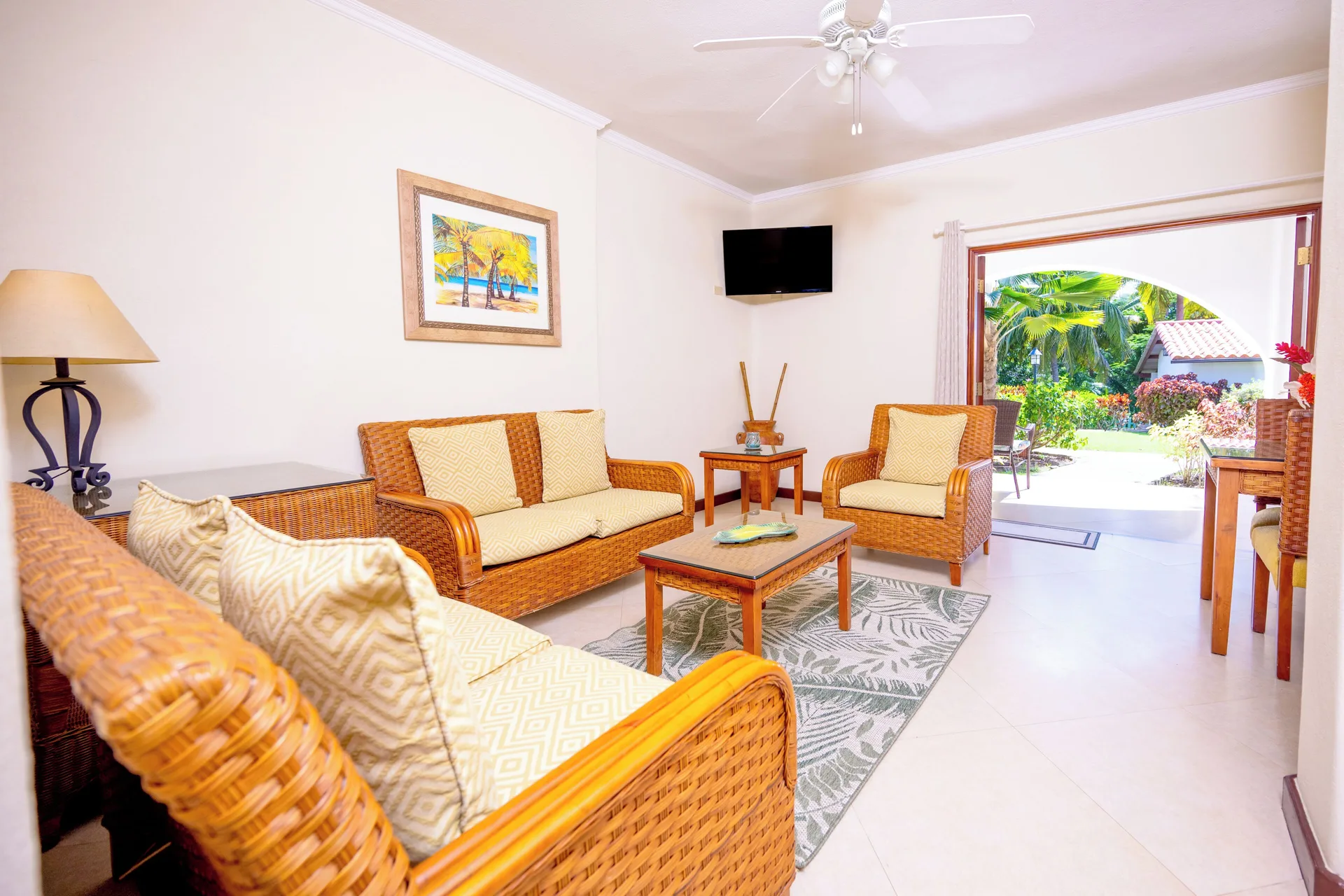 Garden View Suite lounge with wicker sofas and open garden doorway at Sugar Cane Club Hotel And Spa.