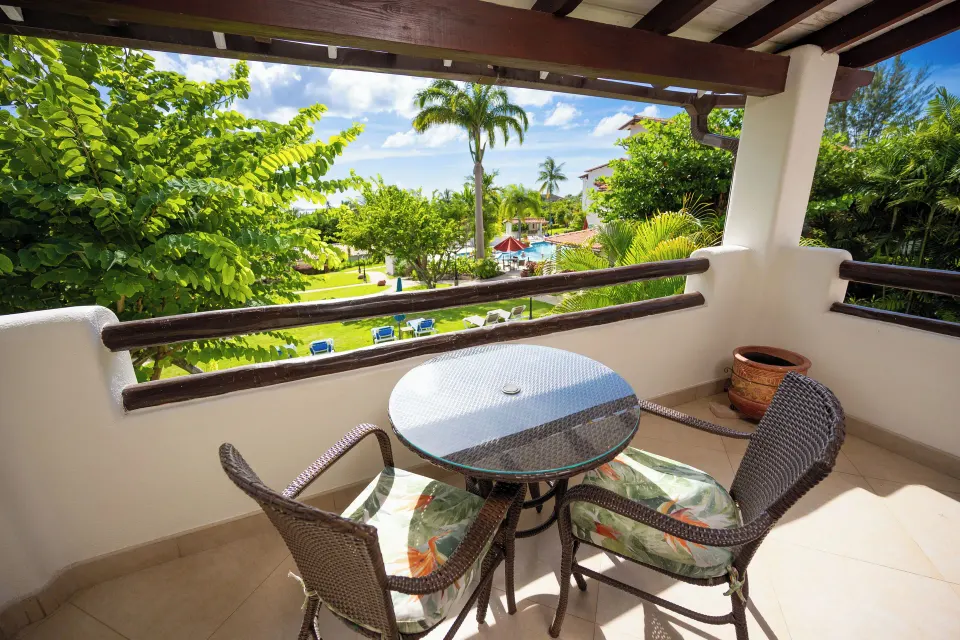 Suite balcony seating overlooking gardens, pool and ocean at Sugar Cane Club Hotel And Spa.