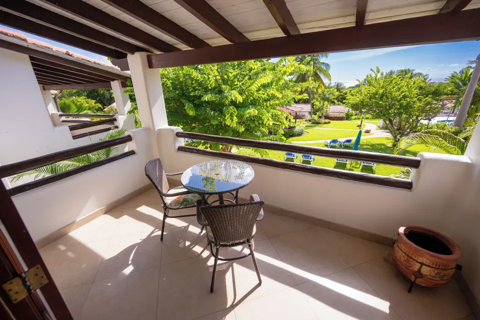 Suite balcony with table, chairs and garden ocean view at Sugar Cane Club Hotel And Spa.