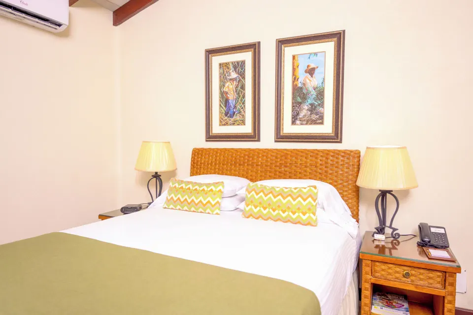 Close view of suite king bed with wicker headboard at Sugar Cane Club Hotel And Spa.