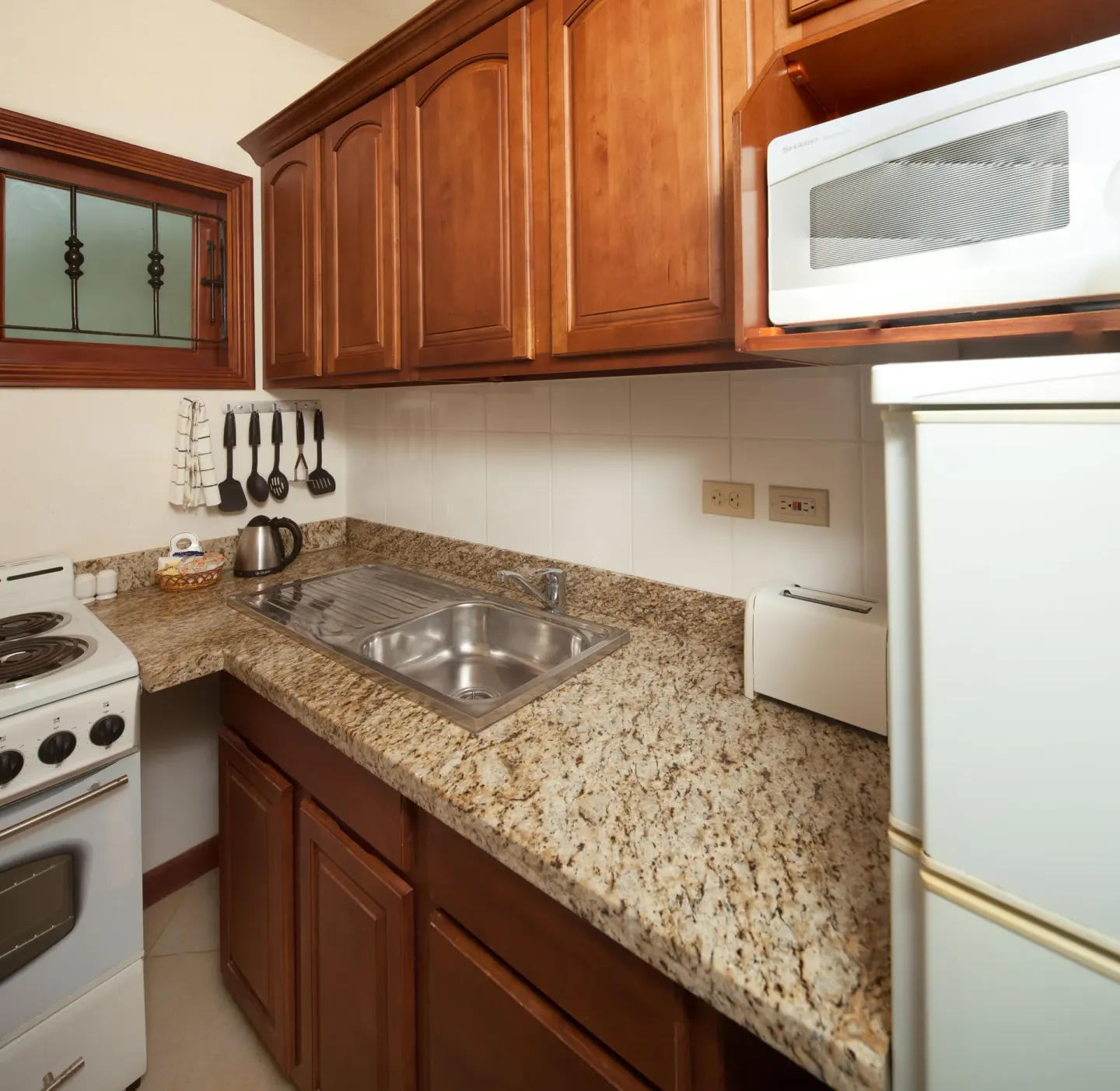 Suite kitchenette with stove, sink, microwave and refrigerator at Sugar Cane Club Hotel And Spa.